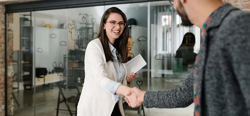 Interview image of woman shaking man's hand, smiling