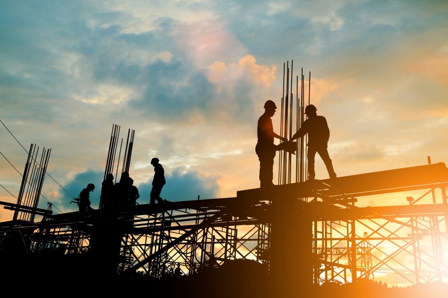 Silhouette of engineer and construction team working at site over blurred background sunset pastel for industry background